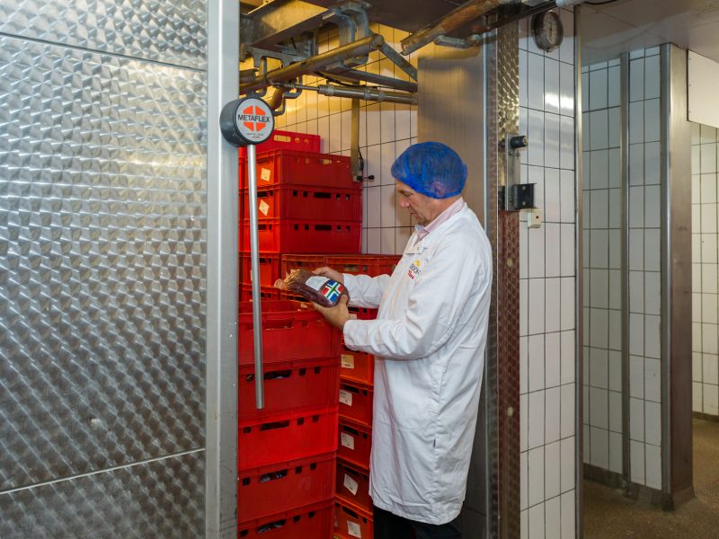 Een slager controleert de verpakking van vlees in de koelcel.