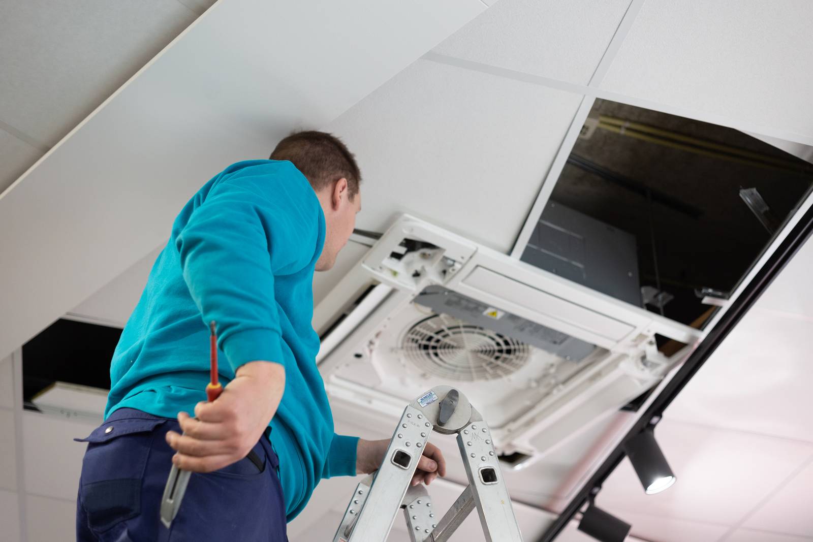 Monteur van Nijmeijer Koelt istalleert een airco systeem op maat in het planfond.