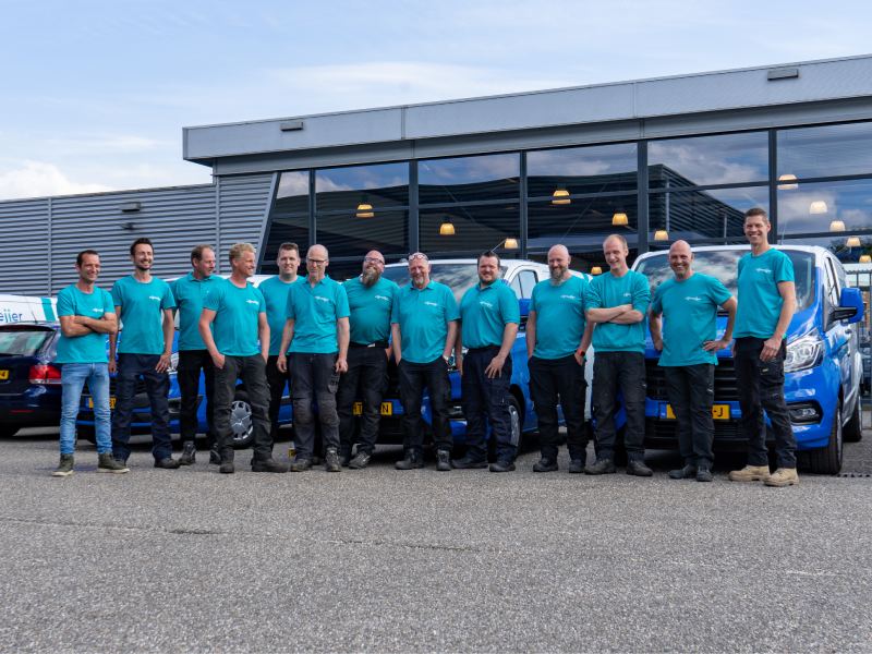 Team van Nijmeijer Koelt staand voor bedrijfsbussen en bedrijfspand.